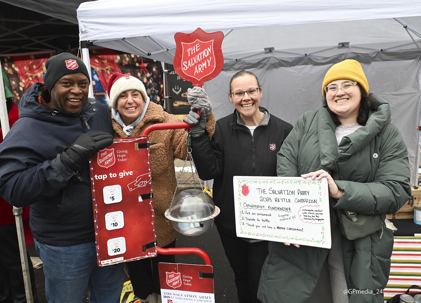 Community volunteers stand at a Christmas kettle during the Milton Miracle on Main festival